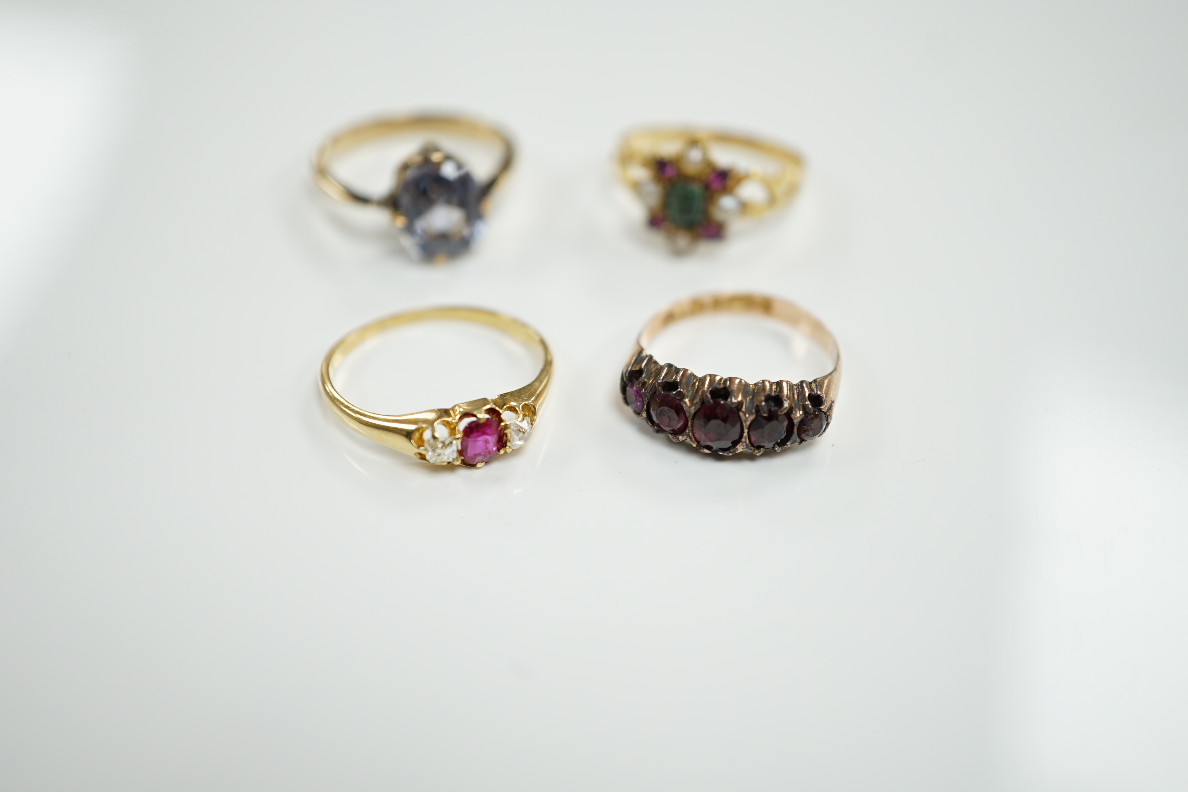 A late Victorian yellow metal, emerald, garnet and split pearl cluster set ring, in the Suffragette colours, size M/N and three other rings including Victorian 9ct gold and garnet set half hoop and 18ct, ruby and diamond